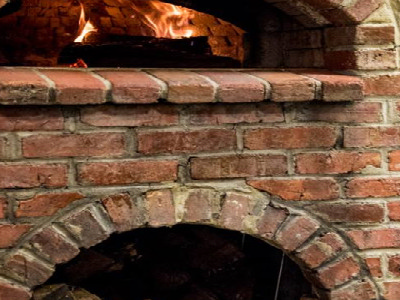 Brick faced, wood fire pizza oven, with a slate plate that reads Carluccis Grill.